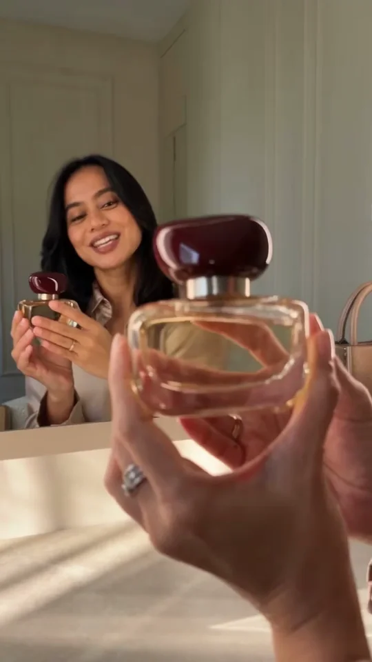 A creator presenting QREED perfume to camera at her vanity